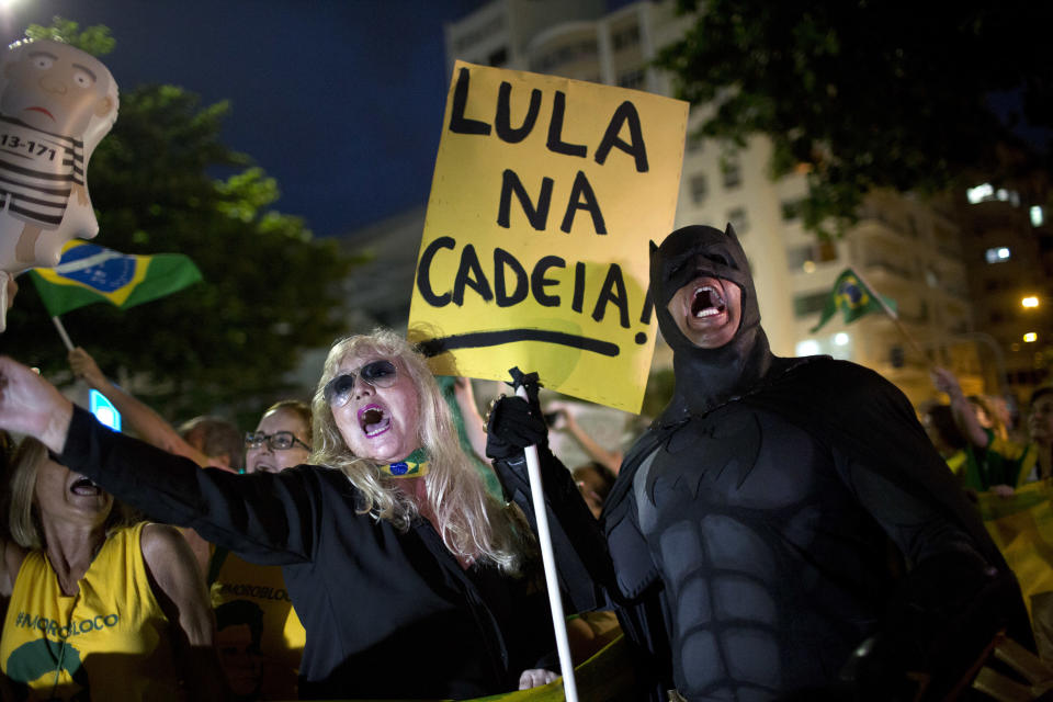 FILE - A demonstrator dressed as Batman holds a sign with a message that reads in Portuguese: "Lula in prison!" during a protest against Brazil's former President Luiz Inacio Lula da Silva, on Copacabana beach in Rio de Janeiro, Brazil, April 3, 2018. Beginning in 2014, the so-called Carwash investigation uncovered a colossal corruption scheme that led to the jailing of several of the country's elite, from former Odebrecht CEO Marcelo Odebrecht to Lula. (AP Photo/Silvia Izquierdo, File)