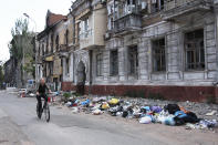 A woman rides a bike past a building damaged during fighting in Mariupol, in territory under the government of the Donetsk People's Republic, eastern Ukraine, Wednesday, May 25, 2022. (AP Photo)