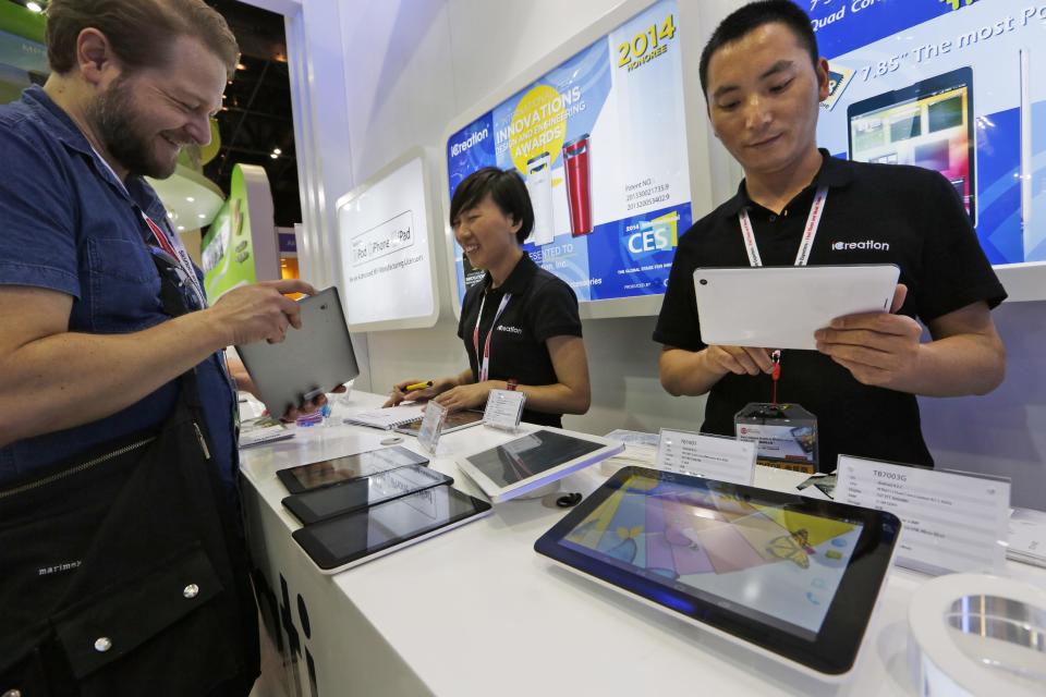In this April 12, 2014 photo, staff members show the Chinese made tablets to a buyer in a booth at the Global Sources Spring China Sourcing Fair in Hong Kong. As China's economy downshifts, manufacturers are bracing for the turning point that’s in store for the world’s second biggest economy. (AP Photo/Kin Cheung)