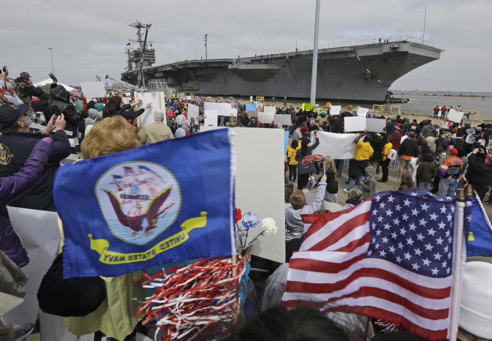 Friends and family wave flags as the nuclear aircraft carrier Harry S. Truman approaches the pier at Naval Station Norfolk in Norfolk, Va., Friday, April 18, 2014. The carrier is returning from a 9-month deployment to the Middle East. (AP Photo/Steve Helber)