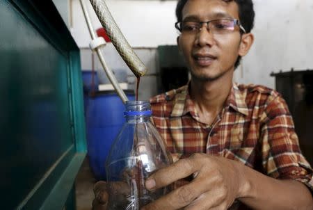 Hamidi collects fuel in a bottle, that was derived from burning plastic waste, at his workshop at TPA Rawa Kucing in Tangerang, Banten province, Indonesia March 17, 2016. REUTERS/Beawiharta