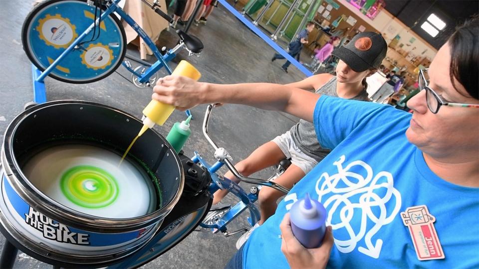 Jenn Borden, director of visitor experience at Keystone Kidspace, works the paint, while Camille Baum, age 10 of Gardners, supplies the power through a specially made bicycle.