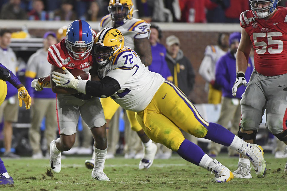 FILE - LSU nose tackle Tyler Shelvin (72) tackles Mississippi wide receiver Elijah Moore (8) during the second half of an NCAA college football game in Oxford, Miss., Saturday, Nov. 16, 2019. LSU coach Ed Orgeron says defensive lineman Neil Farrell has rejoined the team after initially opting out more than a month ago. Orgeron says he's also hearing “rumblings” that defensive lineman Tyler Shelvin could opt back. (AP Photo/Thomas Graning, File)