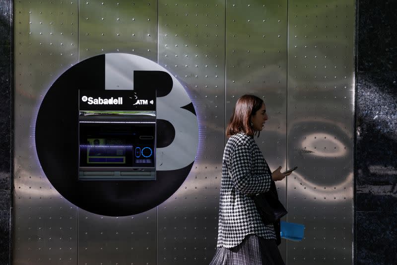 A woman walks past a branch of Spain's Sabadell bank in the Gran Via of Bilbao