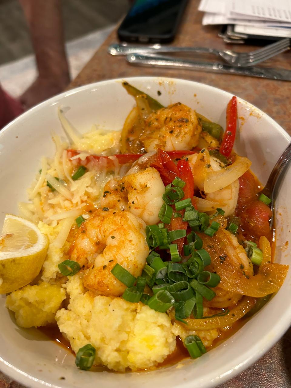 Shrimp and grits feature white cheddar stoneground grits, Cajun shrimp, sauteed cherry tomatoes, shallots, mixed peppers and green onion in a white wine sauce at Caston & Main.