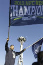 A Seattle Seahawks fan waves a flag with the Space Needle behind at a parade for the Super Bowl champions in Seattle on Wednesday, Feb. 5, 2014. The Seahawks beat the Denver Broncos 43-8 in the NFL Super Bowl XLVIII football game on Feb. 2, 2014. (AP Photo/John Froschauer)