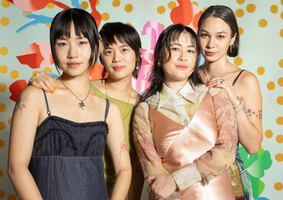 Four women stand together in front of a colorful backdrop.