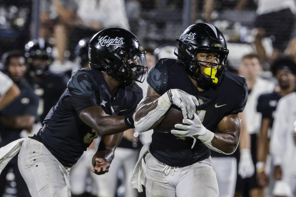 Central Florida running back RJ Harvey, left, takes a handoff from quarterback Timmy McClain during the second half of the team's NCAA college football game against Villanova, Saturday, Sept. 16, 2023, in Orlando, Fla. (AP Photo/Kevin Kolczynski)