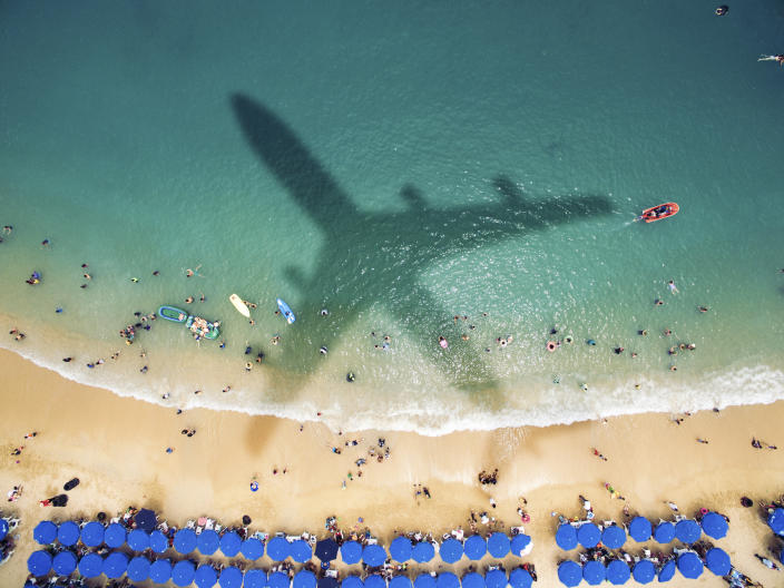 Airplane&#39;s shadow over a crowded beach