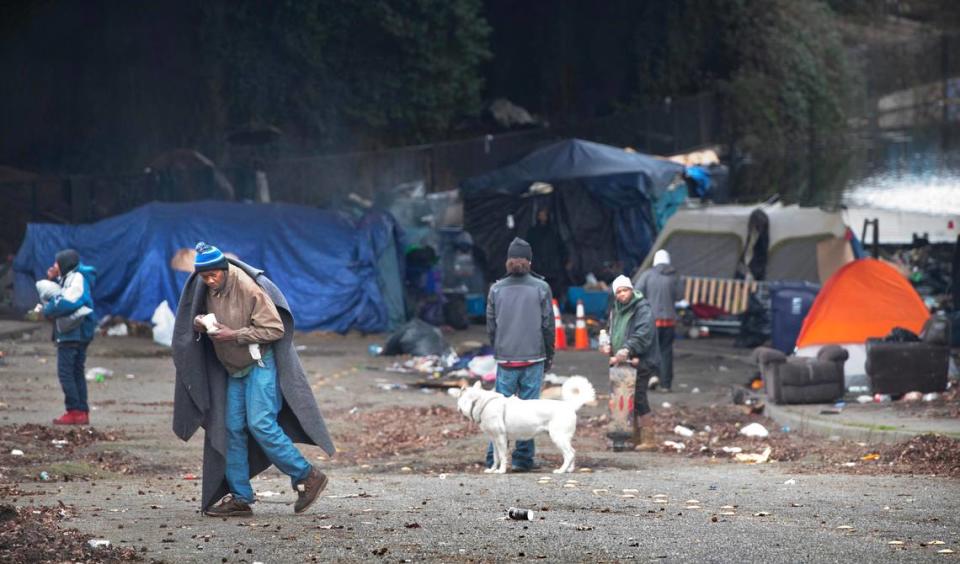 Homeless return to their camp after receiving cups of jambalaya soup and hot barbecue beef sandwiches from “Mr. Terry” Hayes’ “Da Van that know The Man” food truck in downtown Tacoma, Washington, on Monday, Feb. 5, 2023.