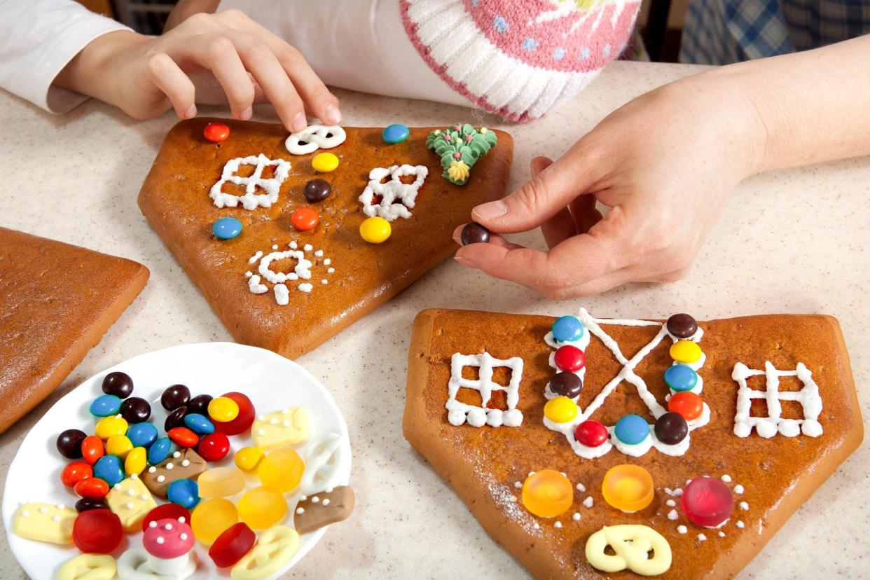 granddaughter and grandmother making the roof of christmas gingerbread house