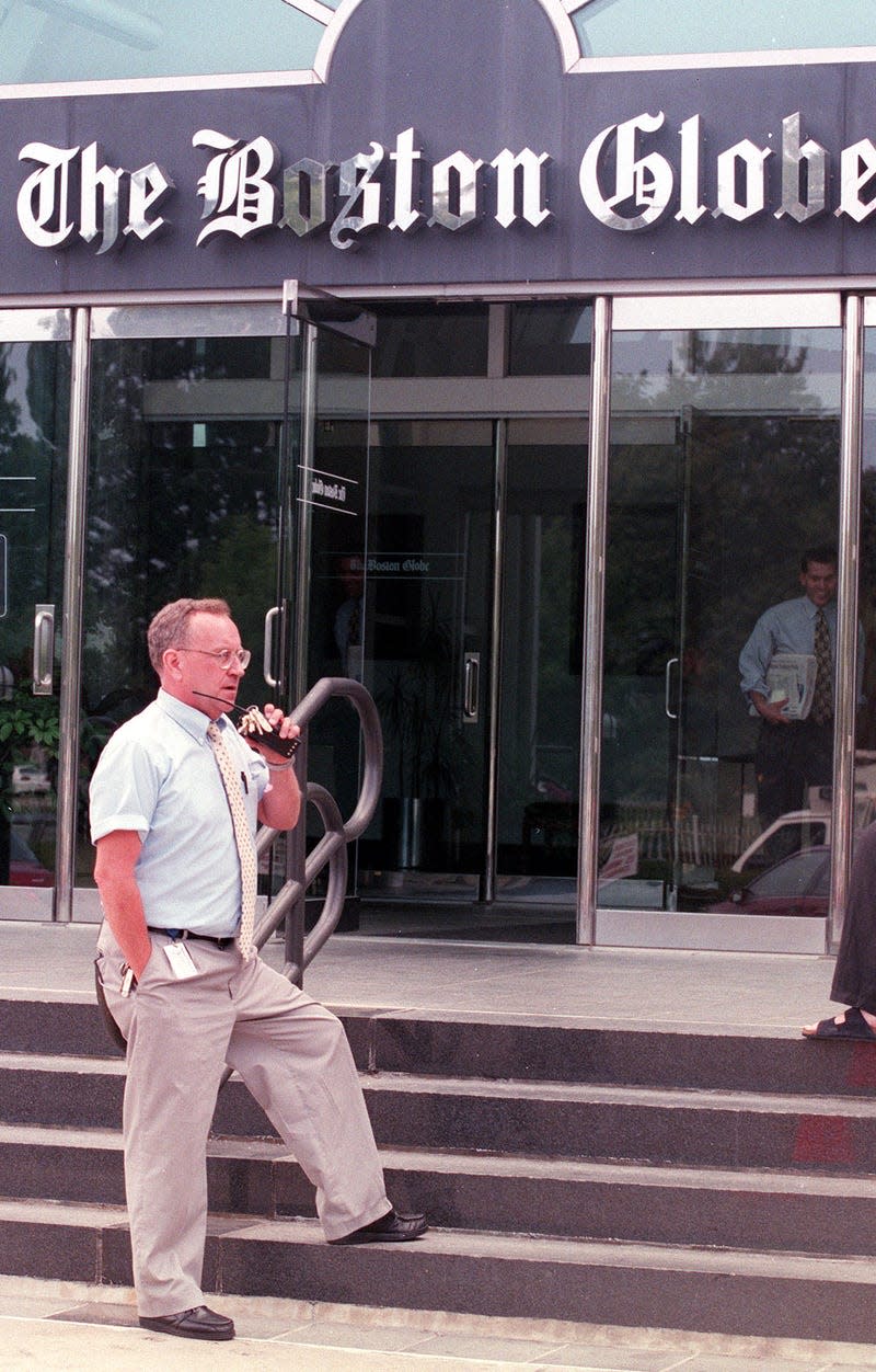 A security guard stands in front of the Boston Globe.
