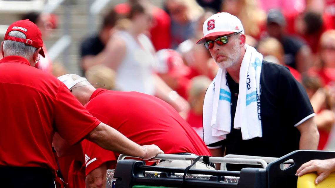 Rob Murphy (right), who was listed as an associate athletic director and director of sports medicine at N.C. State, helps a crew move an injured football player in the first half of N.C. State’s game against JMU at Carter-Finley Stadium in Raleigh, N.C., Saturday, Sept. 1, 2018.