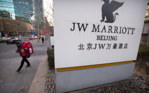 A deliveryman walks away from the entrance of a JW Marriott hotel in Beijing - Credit: AP