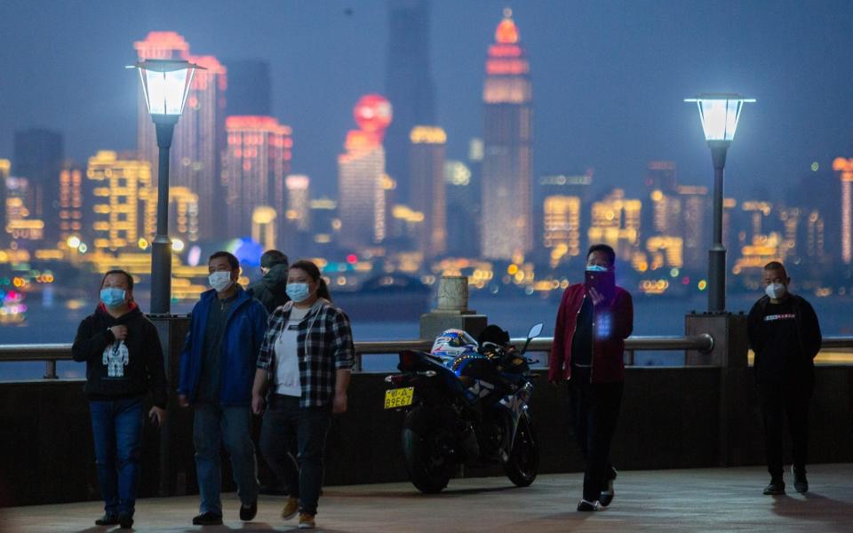 People wearing face masks walk by the river in Wuhan, the Chinese city in which the coronavirus outbreak began - Barcroft Media