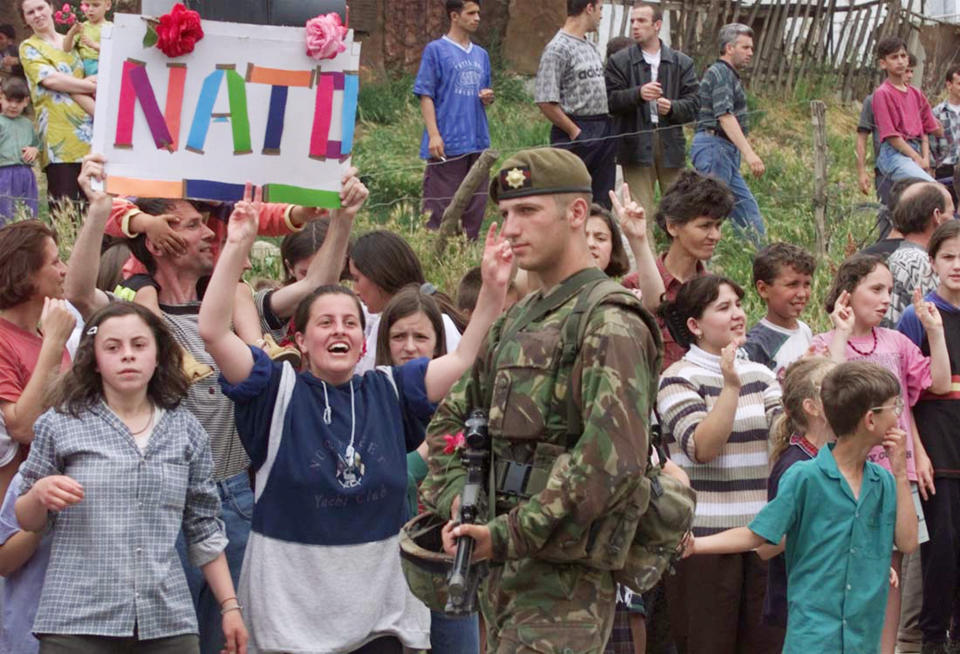 FILE - In this Sunday, June 13, 1999 file photo, ethnic Albanians from Pristina hold up a NATO sign to welcome British NATO soldiers as they entered various parts of the city. It’s exactly 20 years since NATO forces set foot in the former Yugoslav province, after an allied bombing campaign ended Serbia’s bloody crackdown on an insurrection by the majority ethnic Albanian population in Kosovo _ revered by Serbs as their historic and religious heartland. (AP Photo/Santiago Lyon, File)