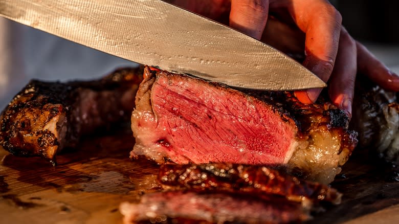 cook slicing meat with knife