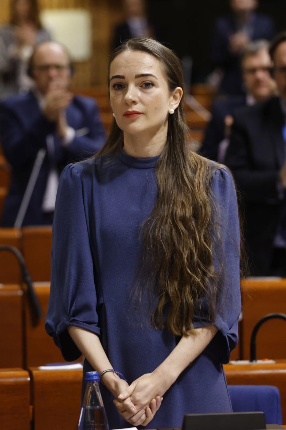 Oleksandra Matviichuk stands with her long hair pulled forward over her shoulder and hands clasped in front of her.