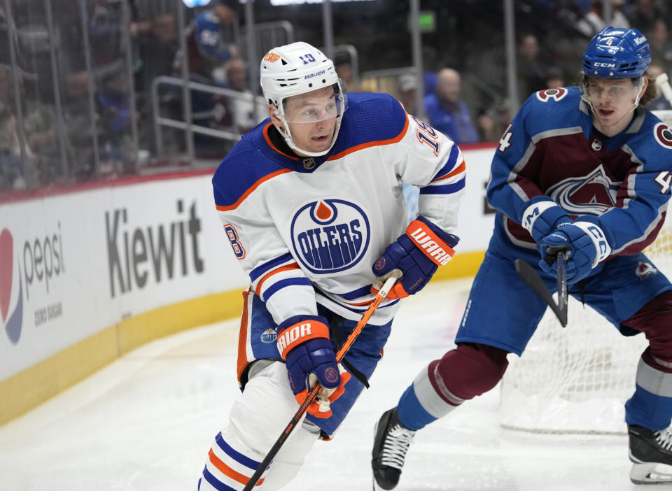 Edmonton Oilers left wing Zach Hyman, left, looks to pass the puck as Colorado Avalanche defenseman Bowen Byram, right, pursues in the second period of an NHL hockey game Sunday, Feb. 19, 2023, in Denver. (AP Photo/David Zalubowski)