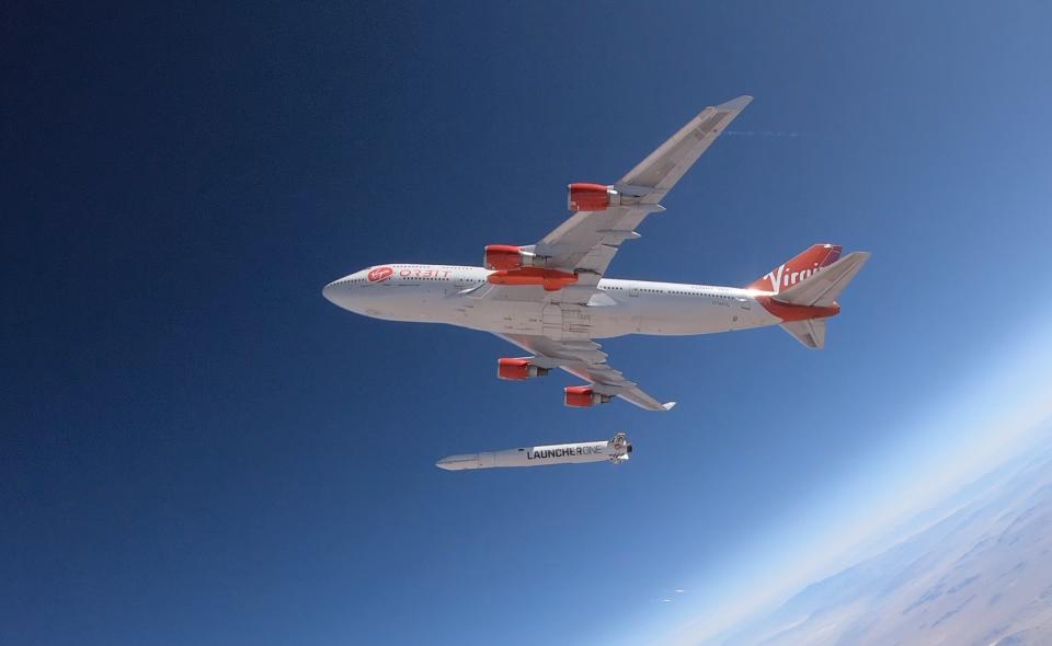 Red and white Cosmic Girl airplane dropping red and white LauncherOne rocket from midair