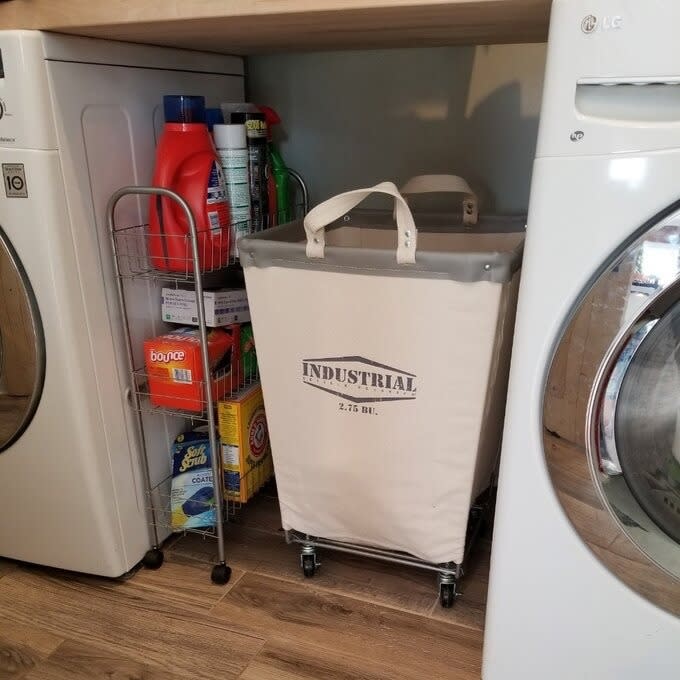 Laundry cart with "INDUSTRIAL 2.5 BBL" text next to a washer and dryer