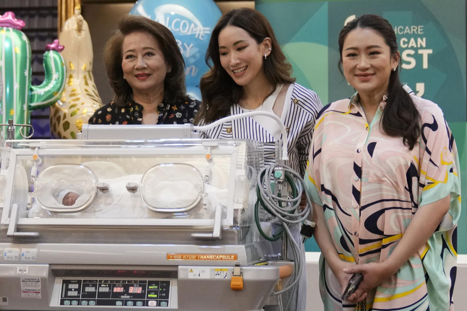 FILE - Paetongtarn Shinawatra, right, a leader of Thailand's opposition Pheu Thai Party, stands behind an incubator with her new born son, along with, left to right, mother Pojaman Na Pombejra and sister Pinthongta Shinawatra, during a press conference in Bangkok, Thailand, May 3, 2023. The Pheu Thai Party is heavily favored to win the most seats in the May 14 general election, and Paetongtarn, daughter of former Prime Minister Thaksin Shinawatra, is one of its three nominees to become the next prime minister. (AP Photo/Sakchai Lalit)
