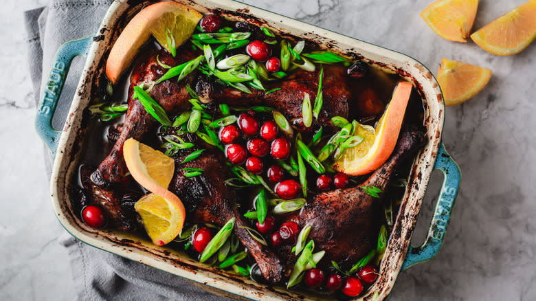 Duck legs, cranberries and orange in casserole dish