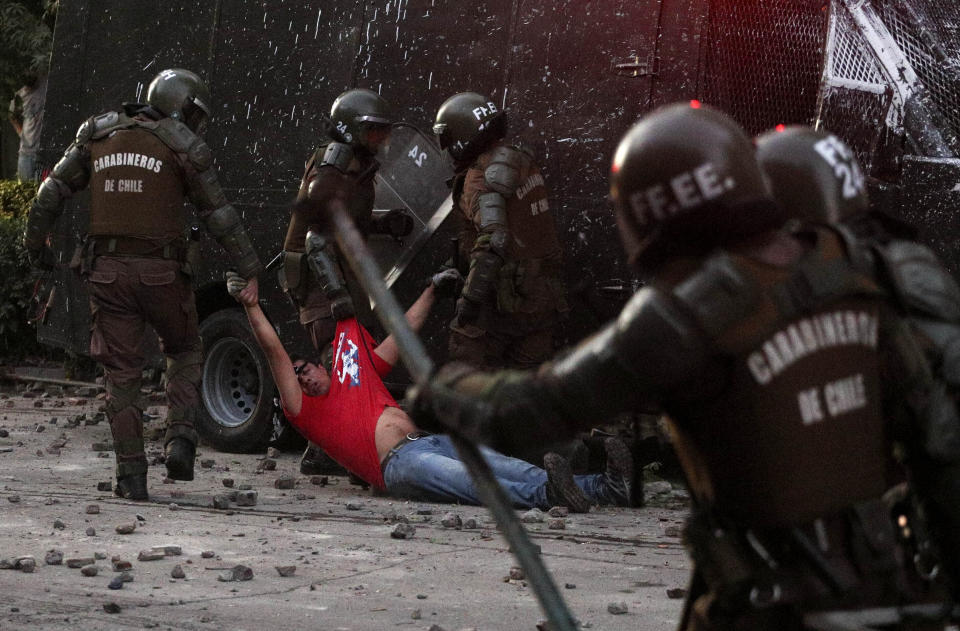 Police drag a detained anti-government protester to a paddy wagon, in Santiago, Chile, Friday, Nov. 29, 2019. Protests sparked by a subway far hike broke out on Oct. 18 and quickly broadened into a social movement demanding greater equality. Most protests have been peaceful, but many evolved into violence, with arson, looting and clashes between masked protesters and security forces. (AP Photo/Esteban Felix)