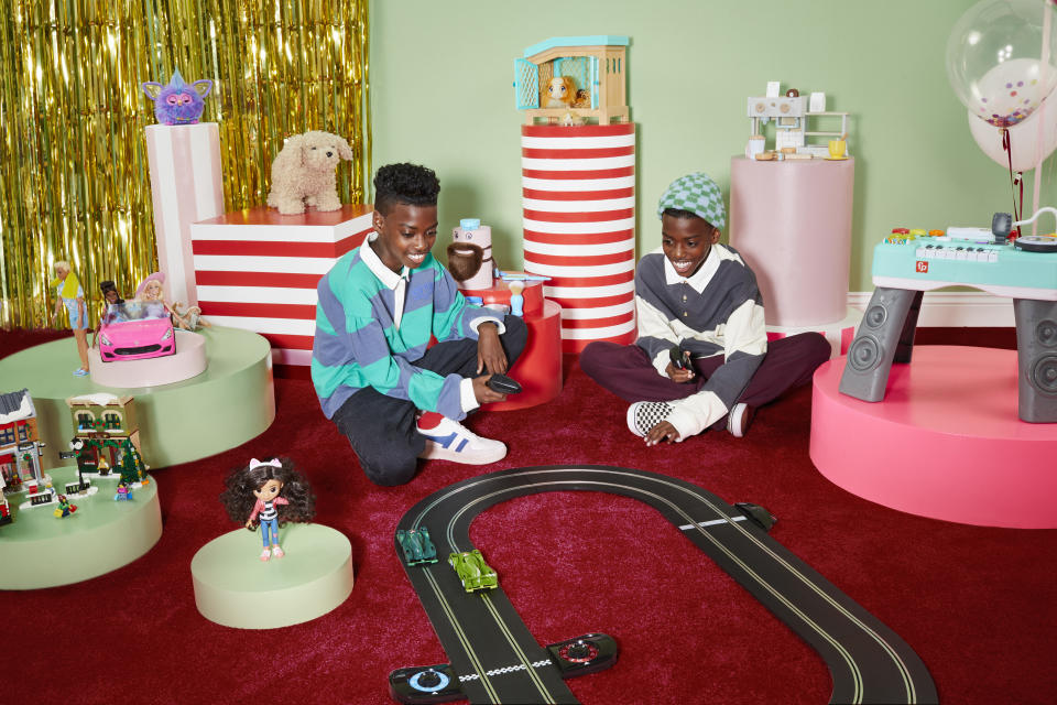 Two kids playing with a racing car track amongst John Lewis' top 10 toys