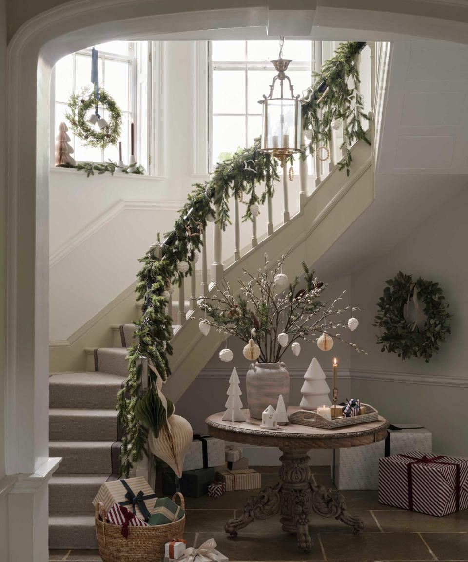 entryway with christmas garlands on bannister, presents and baubles