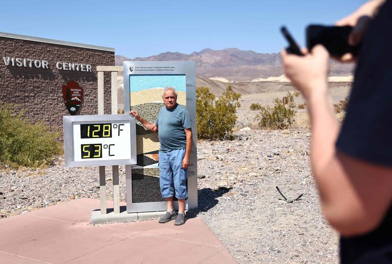 Un turista posa junto a un termómetro no oficial en el calor de la tarde en el Centro de visitantes de Furnace Creek, durante una ola de calor de larga duración que afecta a gran parte del estado 