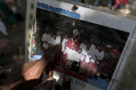 In this Oct. 23, 2018, photo, Laurencius Kollo holds up a photograph taken in July 2009, which shows Marselina Neonbota, (third from left) posing with the district Bishop. Marselina left home eight years ago for a job in Malaysia, a place where some Indonesian migrant workers can earn more money in a few years than in a lifetime at home. She never returned. (AP Photo/Tatan Syuflana)