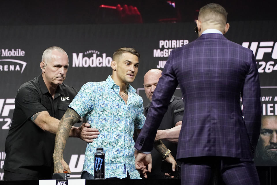 Security holds Dustin Poirier away from Conor McGregor, right, during a news conference for a UFC 264 mixed martial arts bout Thursday, July 8, 2021, in Las Vegas. The two are scheduled to fight in a lightweight bout Saturday in Las Vegas (AP Photo/John Locher)