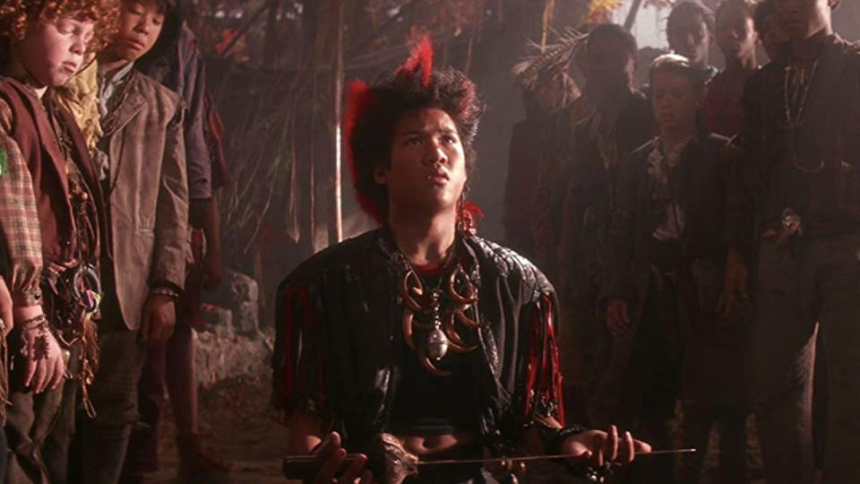 Dante Basco kneeling, as he presents a sword in Hook.