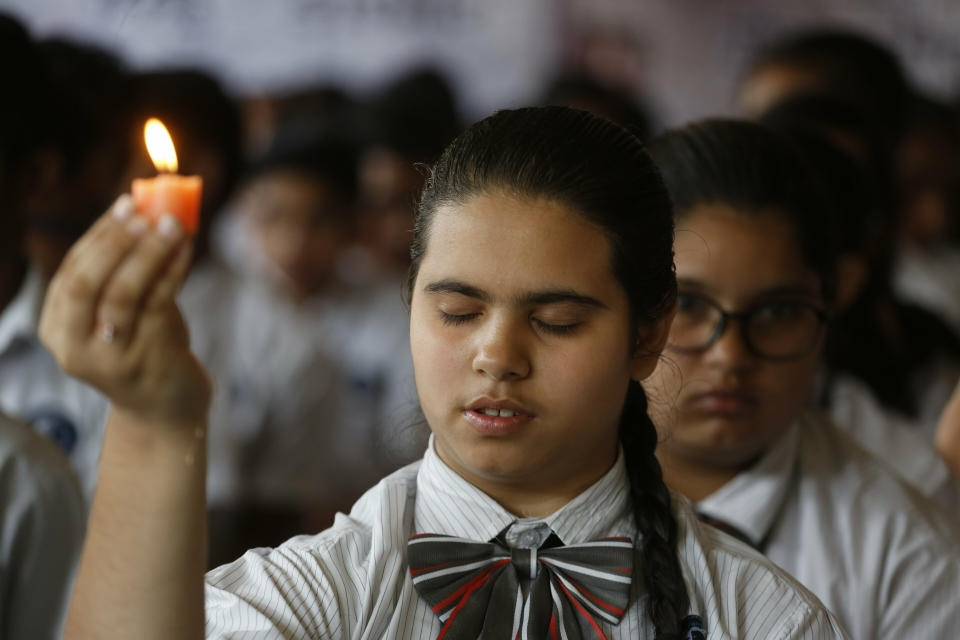 An Indian student holds a candle as she pays tribute to paramilitary soldiers killed in Thursday's explosion in Kashmir, at a school in Ahmadabad, India, Friday, Feb. 15, 2019. The death toll from a car bombing on a paramilitary convoy in Indian-controlled Kashmir has climbed at least 40, becoming the single deadliest attack in the divided region's volatile history, security officials said Friday. (AP Photo/Ajit Solanki)