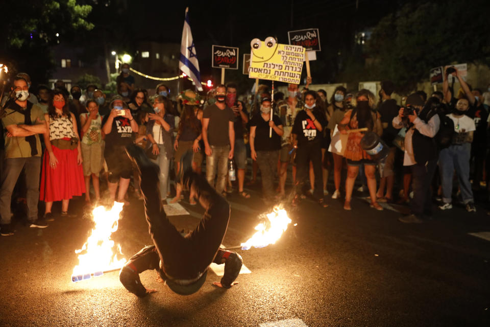 A performer dance with fire during a protest in front of Israel's Prime Minister's residence in Jerusalem, Thursday, July 16, 2020. Hundreds of protesters gathered outside Netanyahu's official residence in Jerusalem to protest against corruption and vent their anger at the economic downtown. (AP Photo/Ariel Schalit)