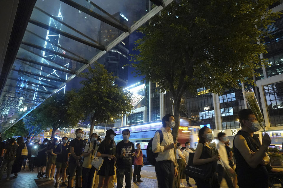 Mourners pay respect on the site to mark the one year anniversary where a man fell to his death after hanging a protest banner against the extradition bill on a building scaffolding in Hong Kong, Monday, June 15, 2020. Protesters in Hong Kong got the government to withdraw extradition legislation last year, but now they're getting a more dreaded national security law, and the message from Beijing is that protest is futile. (AP Photo/Vincent Yu)