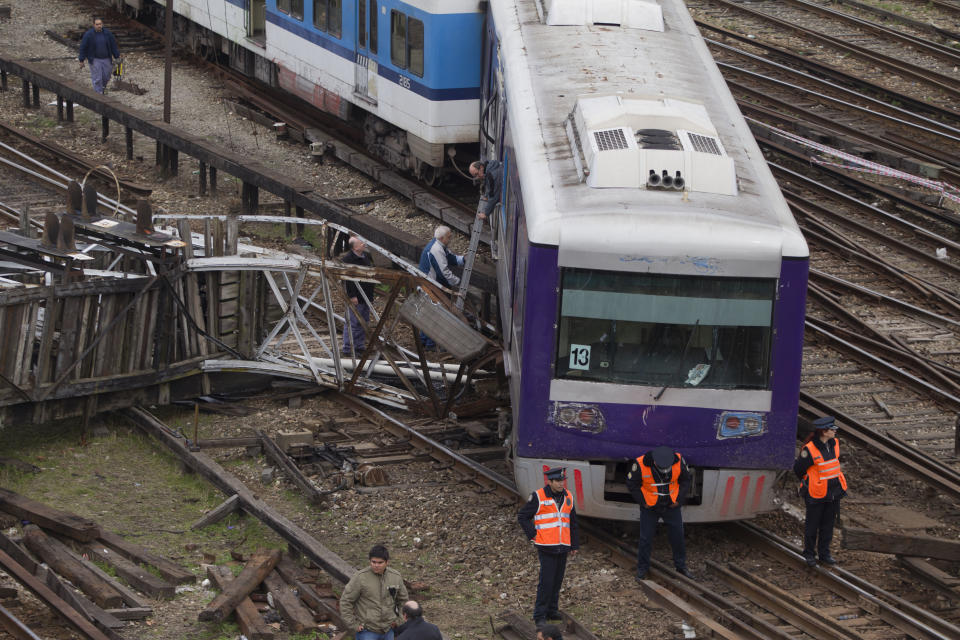 FILE - In this Aug. 6, 2012 file photo, police officers stand in front of a derailed commuter train at the downtown Retiro station in Buenos Aires, Argentina. A court in Argentina has sentenced on Wednesday, Oct. 10, 2018, the former planning minister Julio De Vido for his role in the 2012 train accident that left more than 50 people dead and hundreds injured. (AP Photo/Eduardo Di Baia,File)