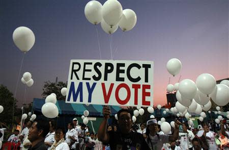 Pro-government supporters hold a placard and white balloons during an election campaign in Nonthaburi province, on the outskirts of Bangkok, January 31, 2014. REUTERS/Chaiwat Subprasom