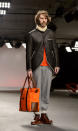 <b>Model, Oliver Spencer</b><br><br>A model at the Oliver Spencer AW13 fashion show wore grey tracksuit bottoms rolled up with tan boots. He sported neon orange accessories.