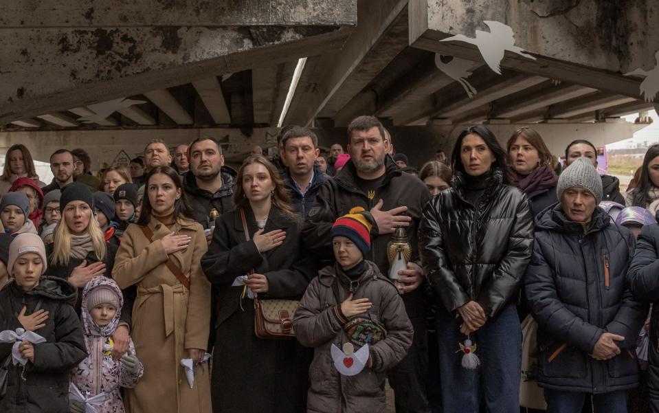 Irpin residents attend a memorial ceremony under a destroyed bridge on the second anniversary of Russia's invasion of Ukraine