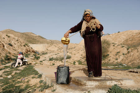 Saliha Mohamedi, 36, fills a bowl from her water storage outside her troglodyte house on the outskirts of Matmata, Tunisia, February 5, 2018. "I don't want to leave my house, it would be as if I was throwing my life and my traditions away," Saliha said. REUTERS/Zohra Bensemra