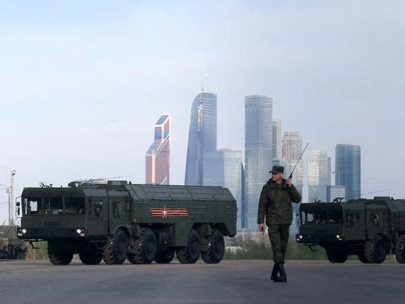 A Russian serviceman walks past Russian Iskander-M missile launchers before a rehearsal for the Victory Day parade, with the Moscow International Business Center also known as