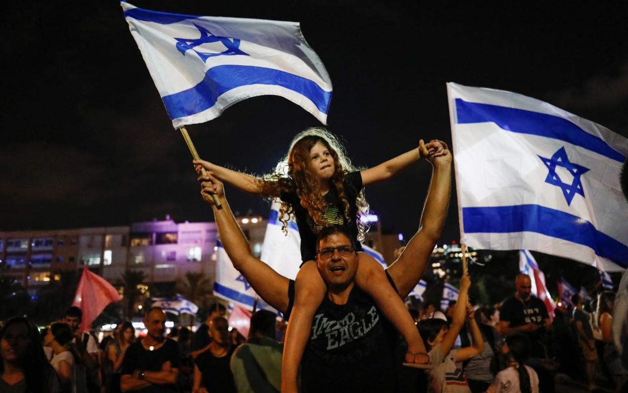People celebrate in Tel Aviv after Israel's parliament voted in a new coalition government, initially to be headed up by Naftali Bennett - CORINNA KERN /REUTERS