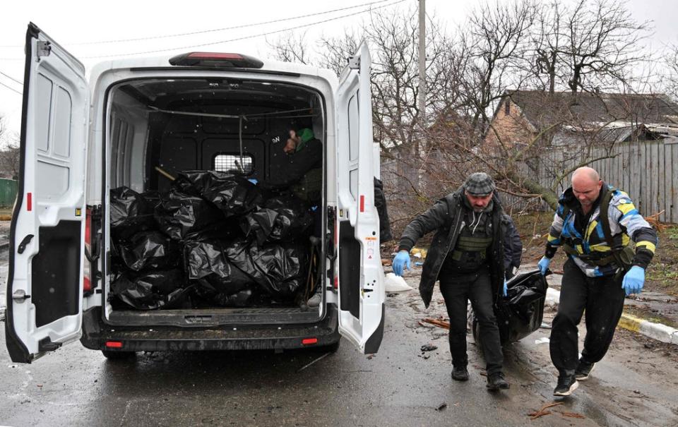 Community workers carry the body of a civilian man killed by Russian shelling in the town of Bucha (AFP via Getty)