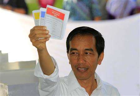 Jakarta governor and presidential candidate from the Indonesian Democratic Party-Struggle (PDI-P) party, Joko Widodo, shows his ballot paper during voting in the parliamentary elections in Jakarta April 9, 2014. REUTERS/Beawiharta