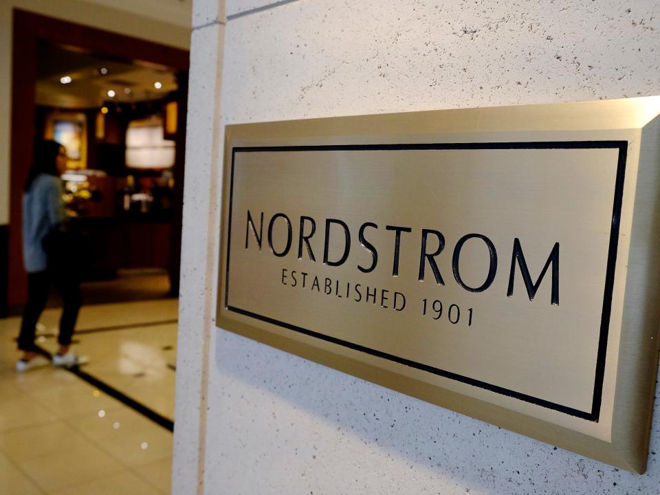 Customer walks in background of sign outside Nordstrom store reading "established 1901"