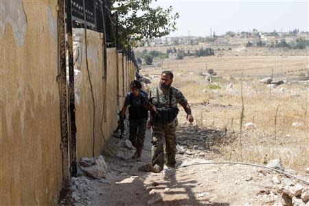 Free Syrian Army fighters walk along a wall beside the Canadian Hospital in Aleppo, August 31, 2013. REUTERS/Molhem Barakat