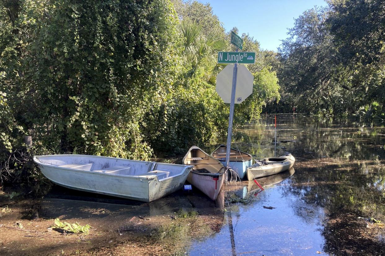 Canoes and kayaks sit tied up to a sign on a flooded street in Seminole County, Fla., on Sunday, Oct. 2, 2022. Residents in central Florida donned fishing waders, boots and bug spray and canoed or kayaked to their homes on streets where floodwaters continued rising Sunday despite it being four days since Hurricane Ian tore through the state.