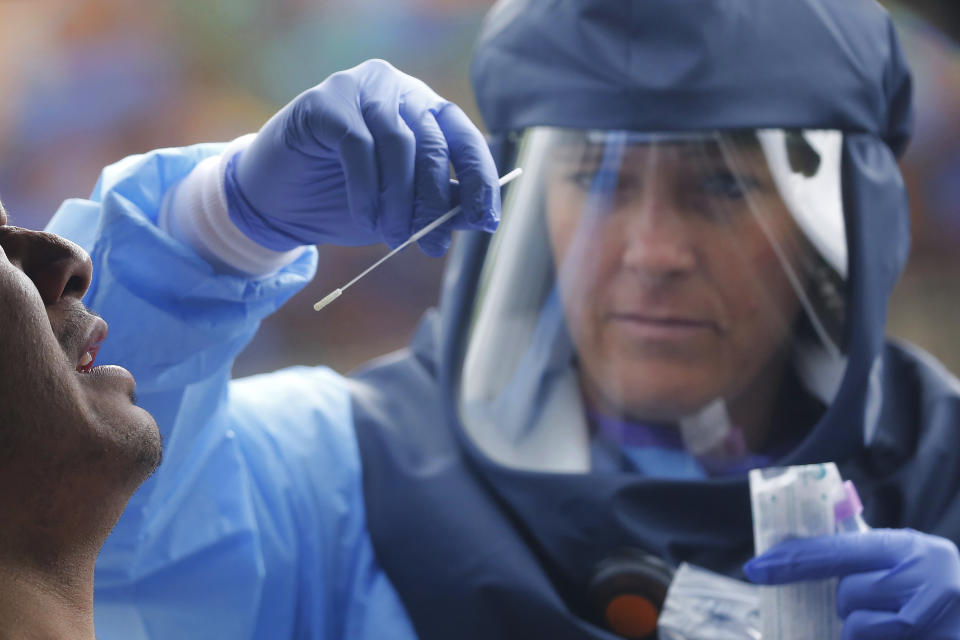 FILE - In this May 20, 2020, file photo, Salt Lake County Health Department public health nurse Lee Cherie Booth performs a coronavirus test outside the Salt Lake County Health Department in Salt Lake City. Public health officials have said robust testing for the coronavirus is essential to safely lifting stay-at-home orders and business closures, but states are creating confusion in the way they are reporting the data. (AP Photo/Rick Bowmer, File)